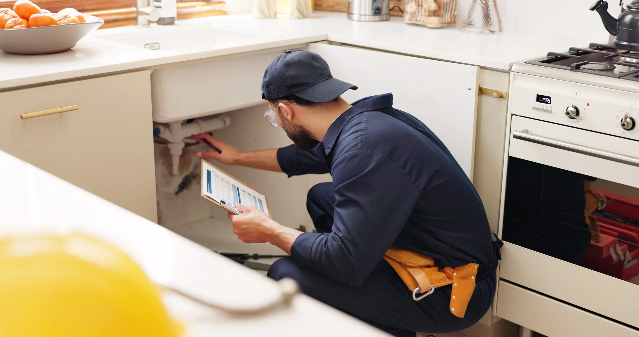 Plumber inspecting pipes under kitchen sink.