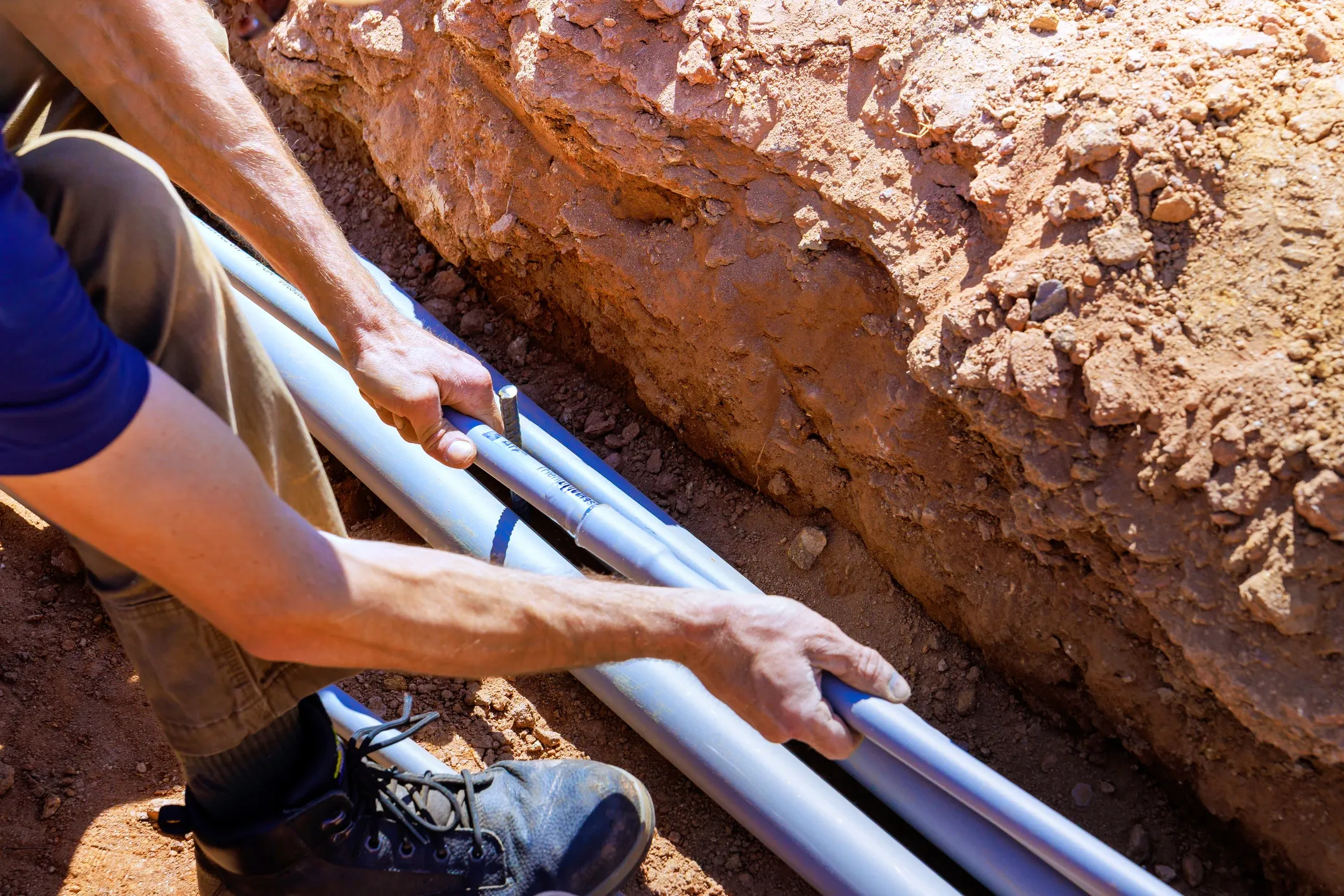 Person installing pipes in a trench.