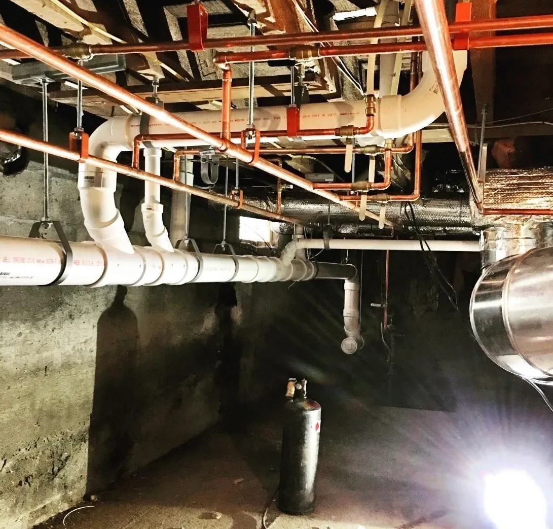 Basement pipes with copper and PVC fittings.
